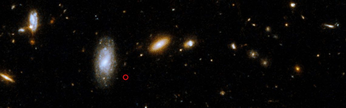 Región del cielo donde apareció la fuente explosiva de rayos gamma GRB 211211A (cuya ubicación se indica con una circunferencia roja), en una imagen captada por el telescopio espacial Hubble. El estallido se asocia a la galaxia espiral barrada que aparece encima y a la izquierda de la marca, situada a unos 1100 millones de años luz, en la constelación del Boyero. [NASA, ESA, Rastinejad et al. (2022) y Gladys Kober (Universidad Católica de América)]